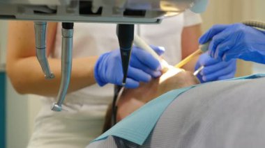 Diş aletlerinden yapılan diş tedavisi iğnesi. Modern dişçilikte tedaviye yakın çekim. Yan görünüş. İşte bir dişçi. Erkek hasta cerrahi müdahaleden ve ağız boşluğu tedavisinden geçiyor. 4 bin.