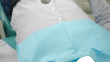 Diş konsepti. Erkek hastaya anestezi yapmak için dişçi ve asistanın şırınga alırken yakın plan çekimleri. Modern diş muayenehanesi. 4k görüntü