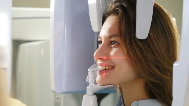 Diş çene taraması. Hasta yüzünde lazer izleri var. Modern dişçilikte ortopedik parlaklık kullanılarak ağız boşluğunda panoramik röntgen çekilen kadın hasta. 4k video — Stok video