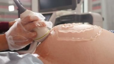 Doğum sonrası ultrason taramaları. Hamile bir kadının ultrason soruşturması. Hamilelik ve Sağlık Hizmetleri konsepti. Doktor klinikte karnına 3 boyutlu ultrason yapıyor. Fetüs ultrasonografisi işlemi. 4k video