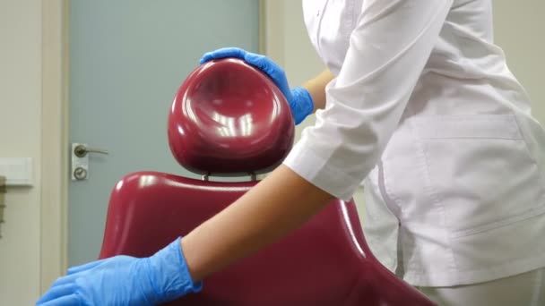 Primer plano de la mujer asistente dental limpiando silla médica con solución desinfectante. Limpieza de la unidad dental médica de esterilización en la clínica dental moderna, centro médico operativo. 4 k imágenes — Vídeos de Stock