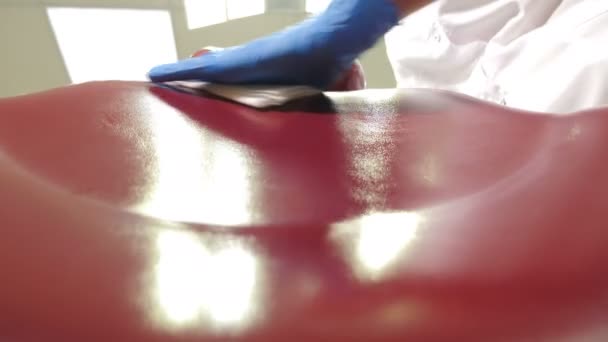 Close-up bottom view of female dental assistant wiping medical chair with disinfectant solution. Cleaning sterilization medical dental unit in modern dental clinic, operating medical facility. 4 k — Stock Video