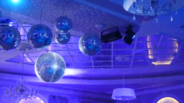 Несколько сверкающих диско-шаров, вращающихся с мигающими огнями во время выступления музыкальной группы или танцевальной вечеринки. Партия зажигает дискотечные шары на синем фоне. Дискотека с яркими лучами, 4 k видео — стоковое видео