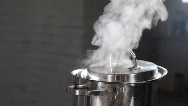 ストーブの上で鍋に沸騰した水から上昇蒸気または蒸気雲。調理中にパンから蒸気。スローモーションで調理プロセス.暗い背景に蒸気と白い煙が立ち上がっている。フルHD — ストック動画