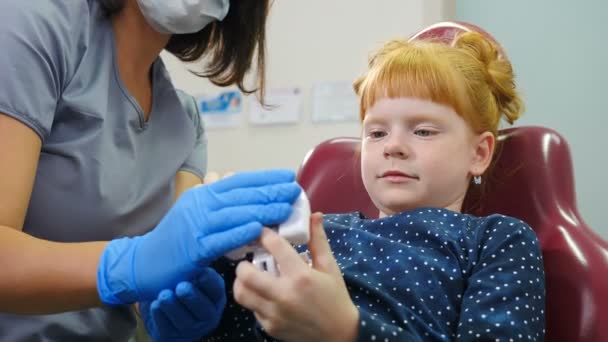 Dentista mostrando a la niña cómo limpiar los dientes con cepillo de dientes correctamente en el modelo de mandíbula en la oficina de dentistas. Cuidado dental, concepto de dientes sanos. 4 k vídeo — Vídeo de stock