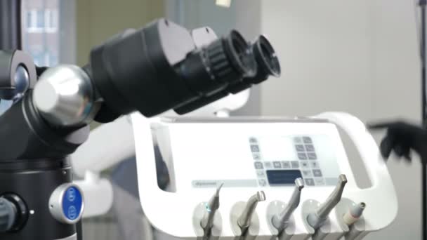 Modern tandvårdsklinik med mikroskop verktyg för behandlingspatienter. Läkarens hand i skyddshandske vidrör medicinsk utrustning. Presentation av utrustning i moderna Clinic. 4 k-film — Stockvideo