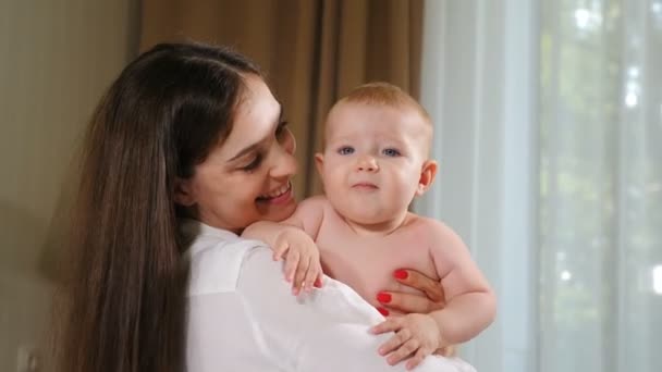 Feliz madre joven mirando a su bebé. Concepto de hijos, bebé, paternidad, infancia, vida, maternidad y maternidad. Hermoso bebé sonriente. 4 k — Vídeo de stock