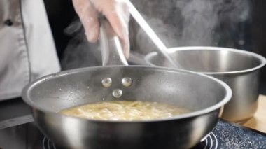 Yavaş çekimde pişmiş risotto. Beyaz duman, arka planda kızgın tavanın üzerinde yükseliyor. Restoranda yemek pişirmek. Mutfakta pişen lezzetli risotto. Tam Hd