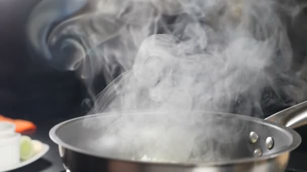 Fumaça branca em câmera lenta subindo acima da frigideira quente no fundo preto. Cozinhar no restaurante. Risoto delicioso sendo cozido na cozinha do restaurante. hd completo — Vídeo de Stock