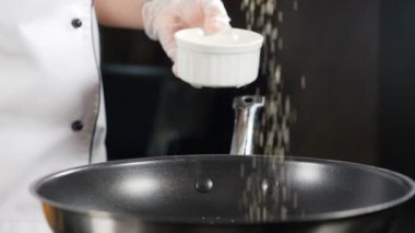 Çikolatalı pasta şefi, meyveli ve dondurmalı flambe tarzı yemek yapıyor. Siyah zemin üzerine düşen beyaz ve kahverengi kamış şekeri. Lezzetli tatlı pişiriyorum. Yemek videosu ağır çekimde çekildi. Tam