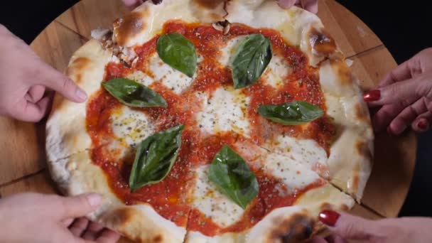 Top view male and female hands taking slices of pizza with cheese, tomato sauce. Slow motion food video. Italian pizza restaurant. Many hands taking pizza from wooden plate. Full hd — Stock Video