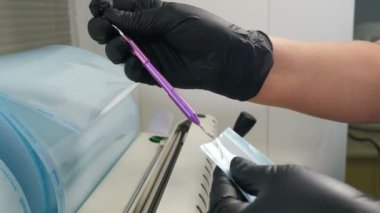 Diş kliniğinde aletlerin sterilizasyonu. Hemşireler dezenfeksiyon için dezenfekte etmeden önce özel kağıt çantalara aletleri yerleştiriyorlar. Yakın plan. 4k video
