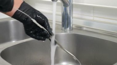 Diş kliniğinde sterilizasyon, bakteriyel arıtma ve dezenfeksiyon. Diş hekimi asistanı dişçi aletlerini musluktan akan suyun altında fırçayla yıkıyor. Yakın plan. 4k video