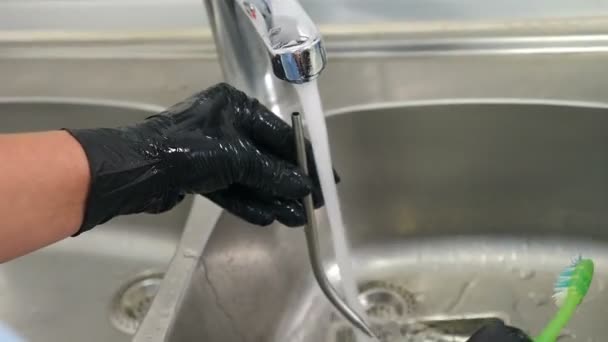 Szerszámok sterilizálás, bakteriális tisztítás és fertőtlenítés a fogászati klinikán. Fogsor tisztítása és mosása fogkefe kis mosogatóban folyó víz alatt. Közelkép. 4 k videó — Stock videók