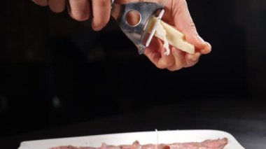 Mutfakta rendelenmiş parmesan peyniri. Restoranda yemek pişirmek. Geleneksel İtalyan mutfağı. Parmesan Shavings ağır çekimde bifteğin üzerine düşüyor. Tam Hd