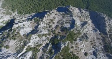 Kırım doğası, kayalar ve dağların havadan görünüşü. Büyük kayalıklara yakın uçuyor. Uçurumlar ve dağlarla kaplı Kırım manzarası. Uçurum yamacı ve dağ hattı. 4k video