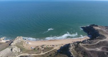 Kırım 'da uçurumları olan güzel deniz kayalıkları manzarası. Karadeniz. Güneşli yaz gününde güzel bir hava aracı manzarası. Seyahat kampı turizmi kavramı. 4k video