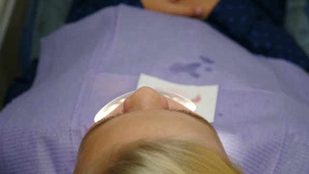 Mały chłopiec robi sobie zęby w dentystyce. Zbliżenie. Widok góry. Pacjent dziecięcy siedzący na krześle dentystycznym w gabinecie stomatologicznym. Asystent i męski dentysta pracujący razem. 4 tys. wideo — Wideo stockowe