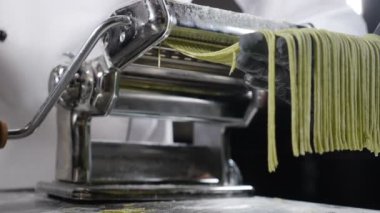 Geleneksel İtalyan mutfağı. Makarna kesmek için makarna yapıyorum. Ağır çekim. Hamur doğrama makinesi. makarna yapma makinesi taze spinage tagliatelle yapmak için. Tam Hd