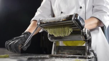 Geleneksel İtalyan mutfağı. Makarna kesmek için makarna yapıyorum. Ağır çekim. Hamur doğrama makinesi. makarna yapma makinesi taze spinage tagliatelle yapmak için. Tam Hd