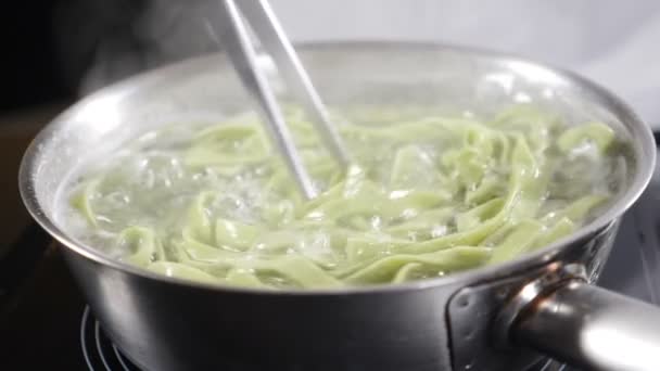 Spaghetti mit cremiger Sauce in der Pfanne kochen und umrühren, Nahaufnahme. Food-Video in Zeitlupe. Köstliche italienische Küche. Gebratene Udon-Nudeln mit Olivenöl und Meeresfrüchten verrühren. Volle Konzentration — Stockvideo