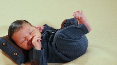 Sevimli, sevimli, 10 günlük yeni doğmuş bebek çocuk örgü örerek uyuyor fotoğraf bölgesinde yastığa uzanmış, yüzünü buruşturuyor, esniyor ve surat yapıyor. Çocukluk, çocukluk, ebeveynlik, annelik. 4k video