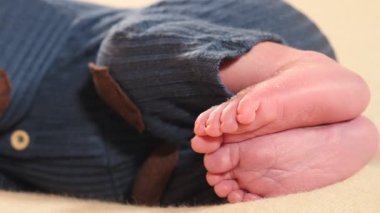 Minik sevimli pembe bebek ayakları. Örgü takım elbiseli bir çocuk. Tatlı çocuk uyuyordu. Güzel bacaklarına ve ayaklarına odaklan. Çocukluk, çocukluk, ebeveynlik, annelik. 4k video