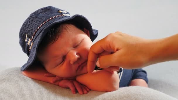 Kleine schattige pasgeboren baby jongen slapend gekleed in hoed en gebreid kostuum met gestripte mouwen, hand onder zijn hoofd. Moeder die zijn huid aanraakt en streelt. 4 k video — Stockvideo