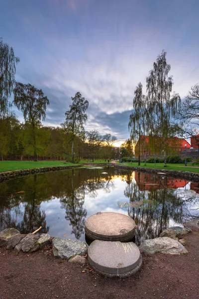 Pond with reflection of house and trees and sun light.