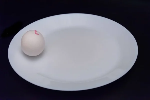 两个白蛋在黑色桌子上的白板上滚动 — 图库照片