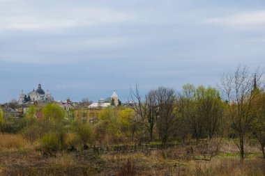 Farklı itiraflar antik kiliselerin siluetleri, sabahları ağaçlar arasında, Ukrayna Lutsk bahar gökyüzü arka plana karşı.