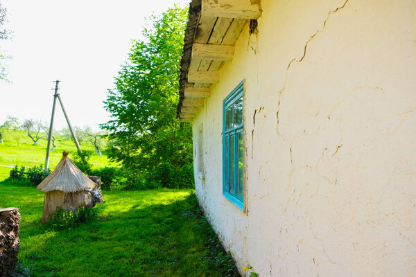 The wall of an old building with wooden windows. Ukrainian folk dwelling in the countryside. The walls are painted with white clay. Ukrainian nature.