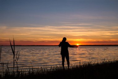 Svityas kıyısında 58 yaşında adam Ukrayna'da yaz gün batımı hayran. Güneş adamın avucunun üzerinde..