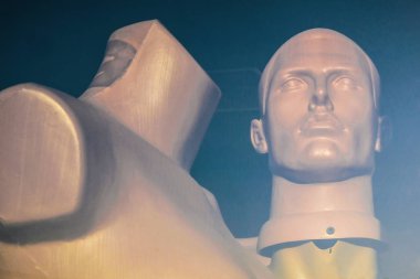 Şafakta pencere camın arkasında iki manken. Bir manken başsız. Plastik insanlar.