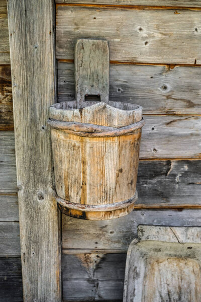 Ancient wooden bucket of handmade work in the yard of folk dwelling in the Carpathians in Ukraine. Ukrainian tourism.