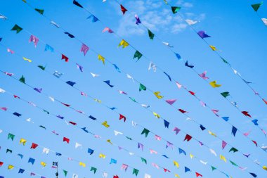 Birçok renkli bayraklar mavi gökyüzüne karşı rüzgarda çırpınıyor. Tatil dekorasyonu.