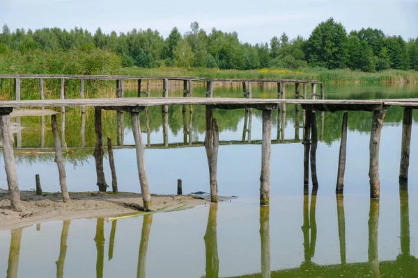 Ukrayna 'da kuraklıkta bir gölde terk edilmiş iki eski ahşap köprü. El işi köprüleri.