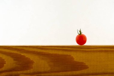 Beyaz bir arka plan üzerinde ahşap bir yüzey üzerinde bir kuş üzümü domates. Minimalizm. Seçici odak. Kopyalama alanı.