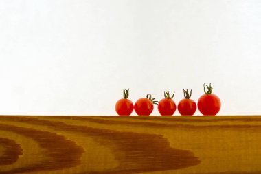  Beyaz arka planda ahşap bir yüzey üzerinde beş frenk üzümü domatesi. Minimalizm. Seçici odaklanma. Ürünler çevrimiçi kavram. Boşluğu kopyala.