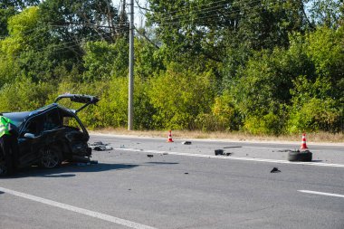 Yolda araba kazası. Kırık bir araba ve enkaz geçidi engelledi. Yol konileri tehlike uyarısı.