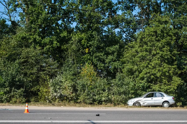 Otoyol yakınlarında çarpışma sonucu araç hasar gördü. Kazadan sonra yol enkazında. Trafik konisi tehlike konusunda uyarır. Ukrayna.