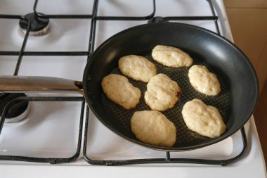 Kızartma tavasında maya krepleri. Ukrayna 'daki mutfakta, gaz ocağında tava kızartma. Akşam güneşi mutfağı aydınlatıyor..