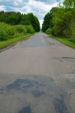 Ukrayna 'da yağmurdan önce terk edilmiş yol. İki tarafta da orman var. Uzayı kopyala Dikey resim.