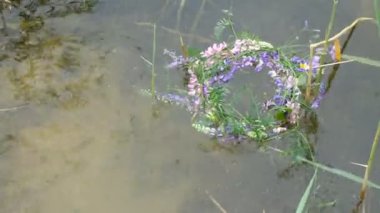Yazın Ukrayna 'da su yüzeyinde renkli kır çiçekleri çelengi. Su dalgaları. İvan Kupala 'nın Pagan bayramı.