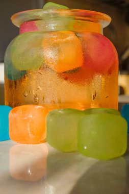 Renkli buz küpleriyle dolu bir kavanoz soğuk içecek. Camda buhar var. Boşluğu kopyala. Dikey resim.