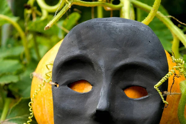 Fragment Keramické Černé Masky Prázdnýma Očima Pozadí Oranžové Dýně Strašidelný — Stock fotografie