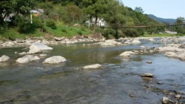 Ukrayna 'nın Zakarpattia bölgesindeki Kvasy köyündeki Kara Tisza Nehri. Nehir üzerindeki askıya alınmış köprü.