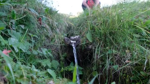 カルパチア人 ウクライナの春の水 水は木製のガターを流れ落ちる 丘の上の男が川を見ている — ストック動画