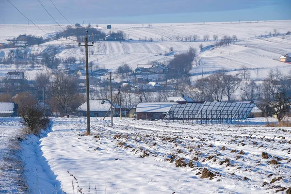 Ukrainian rural landscape with snow on a sunny winter morning. Solar panels in winter.