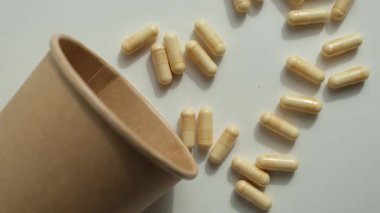 Kapsüllerdeki besin takviyeleri biyolojik olarak çözünebilir kağıt bardakların yanında. Uygun kullanım ve imha. Sürdürülebilir haplar.